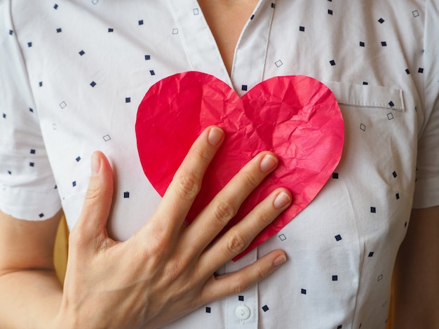 Gerimpeld hart in vrouwelijke handen. Het symbool van een gebroken hart. Valentijnsdag concept.