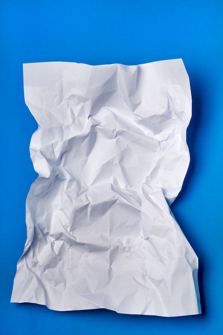 Foto gerimpeld wit stuk papier op een blauwe achtergrond.