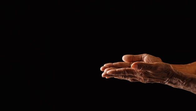 Gerimpelde oude man's hand met lege hand op donkere achtergrond