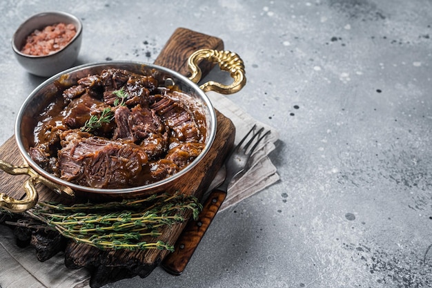 写真 茶色の赤ワインソースで煮込んだドイツの牛肉の頬灰色の背景上面図コピースペース