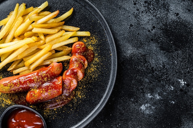 Salsicce al currywurst tedesco con patatine fritte su un piatto