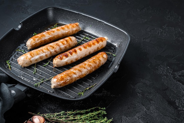 German grilled Bratwurst sausages in a grill pan. Black background. Top view. Copy space.