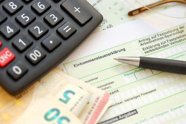 German income tax return form with pen and european euro money\
bills lies on accountant table close up taxpayers in germany using\
euro currency to pay taxes