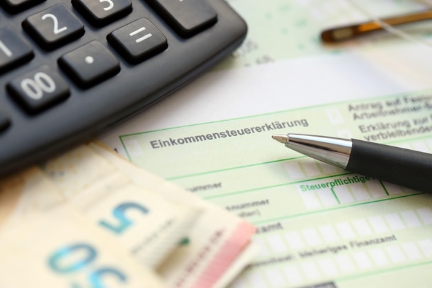 German income tax return form with pen and european euro money bills lies on accountant table close up Taxpayers in Germany using euro currency to pay taxes