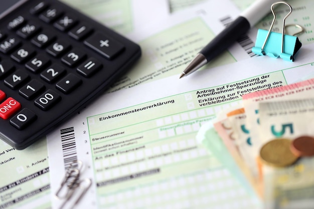 German income tax return form with pen and european euro money bills lies on accountant table close up Taxpayers in Germany using euro currency to pay taxes