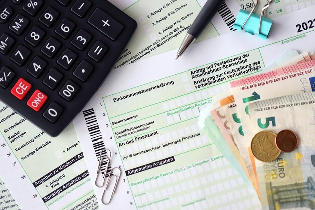 German income tax return form with pen and european euro money bills lies on accountant table close up Taxpayers in Germany using euro currency to pay taxes