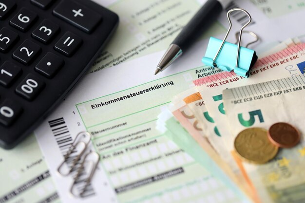 German income tax return form with pen and european euro money\
bills lies on accountant table close up taxpayers in germany using\
euro currency to pay taxes