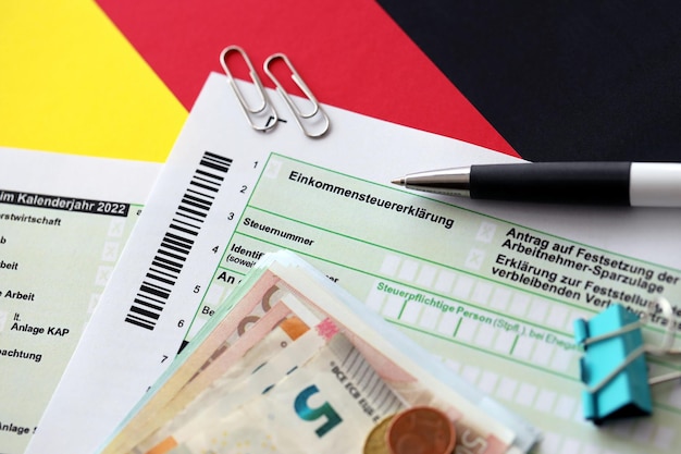 german income tax return form with pen and european euro money bills lies on flag close up taxpayers in germany using euro currency to pay taxes