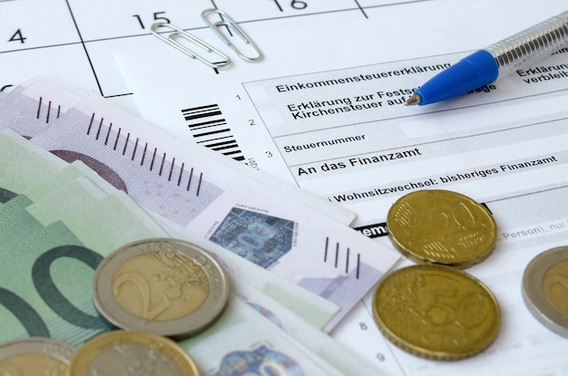 Il modulo fiscale tedesco con penna e banconote europee si trova sul calendario dell'ufficio i contribuenti in germania utilizzano la valuta euro per pagare le tasse