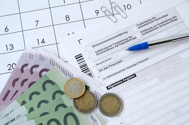 German tax form with pen and european money bills lies on office calendar Taxpayers in Germany using euro currency to pay taxes