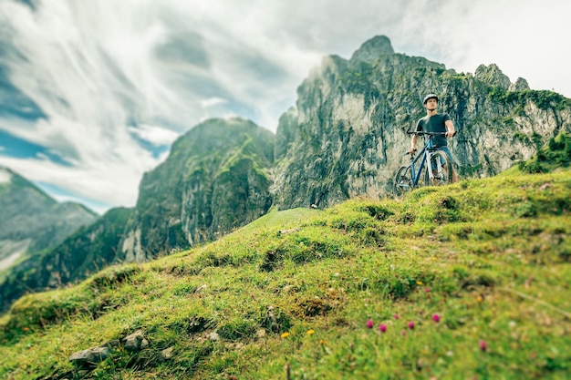 Germany, Bavaria, Pfronten, young man with mountain bike on alpine meadow near Aggenstein