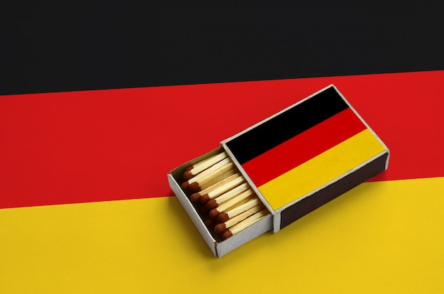 Germany flag  is shown in an open matchbox, which is filled with matches and lies on a large flag