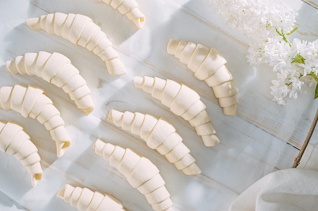 Gerold croissant deeg en klaar voor het bakken op een witte houten tafel op bakpapier in de ochtendzon