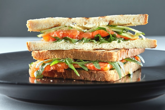 Gerookte zalm sandwich op rogge met rucola, roomkaas op het bord