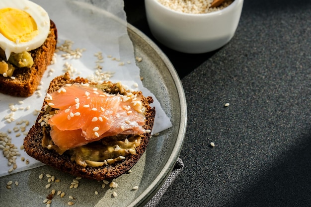 Geroosterd brood met gepocheerde eieren, avocado en zalm. Guacamole-broodjes. Gezond ontbijt. Olijfolie. Sesam zaden. Vegetarisch gezond eten.