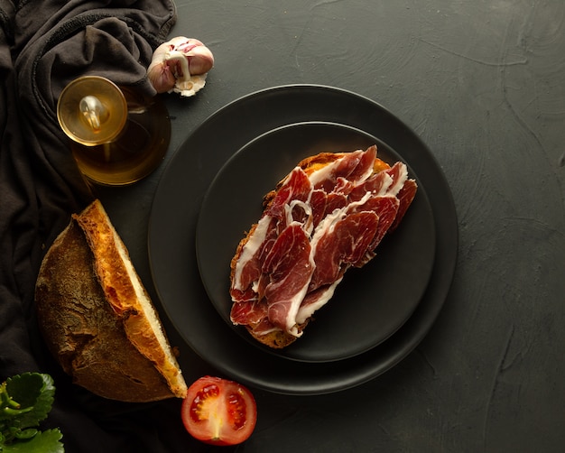 Geroosterd brood met Iberische ham op zwarte platen en rustieke achtergrond
