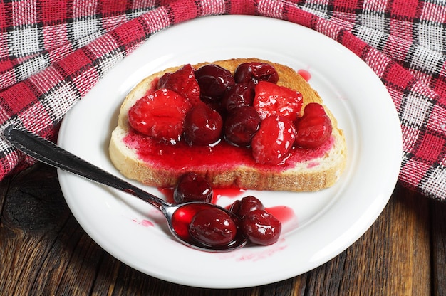 Geroosterd brood met ingeblikte kersen en aardbeien op rustieke houten tafel