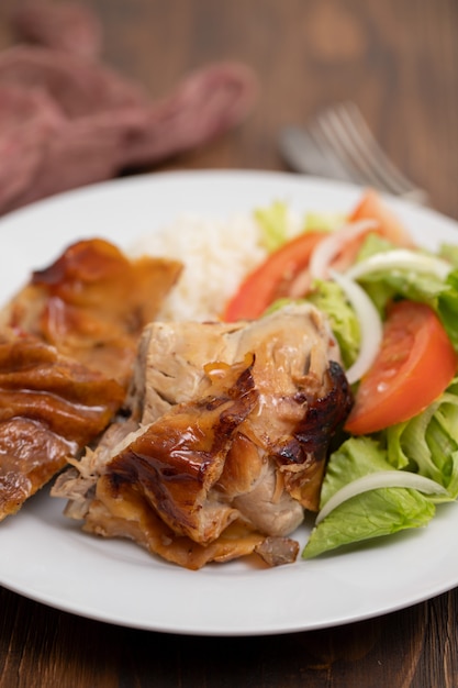 Geroosterd varkensvlees met gekookte rijst en salade op witte plaat