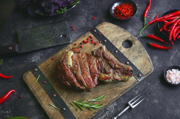 Geroosterd vlees en groenten op een donkere achtergrond, chilipeper, vleeskwekerij, peterselie en kruiden, Ribeye Steak, Ingrediënten voor het koken, Selectieve aandacht