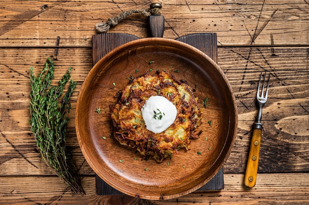 Geroosterde Aardappelpannenkoekjes of Fritters met kruiden in een houten bord. houten achtergrond. Bovenaanzicht.