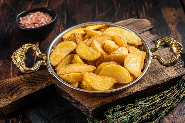 Geroosterde aardappelpartjes met tijm in een koekenpan Houten achtergrond Bovenaanzicht