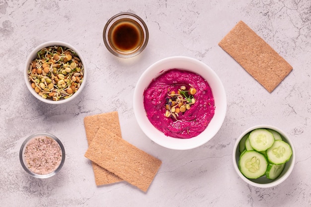 Geroosterde Bieten Hummus met gekiemde granen, komkommer en knäckebröd, bovenaanzicht.