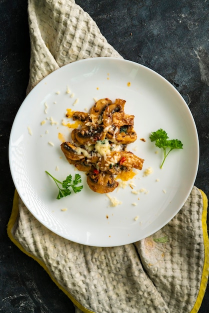 Geroosterde champignons met kaassaus in een wit keramisch bord met kruiden
