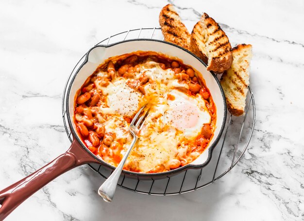 Geroosterde eieren met tomatensaus bonen en kaas heerlijke ontbijt lunch tapas op een lichte achtergrond