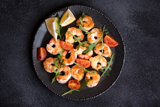 Geroosterde garnalen met tomaten en rucola op zwarte plaat