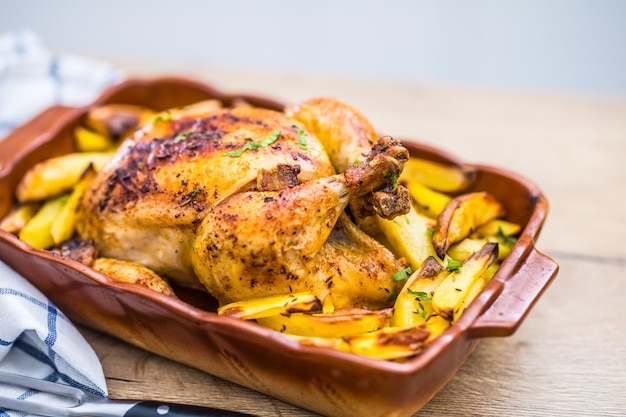 Geroosterde hele kip met aardappelen in ovenschaal. Lekker eten thuis op het aanrecht.