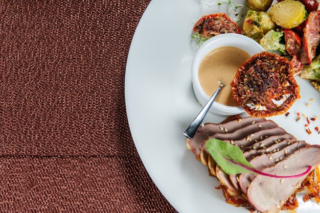 Geroosterde kabeljauwrolletjes geserveerd met gierst en gestoomde broccoli, wortel, spruitjes en courgette