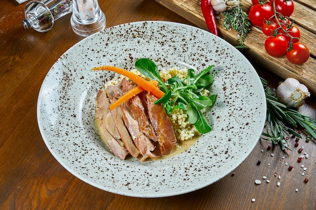 Geroosterde kalkoenfilet met bulgur en spinazie in een beige, keramische plaat op een houten tafel. Voeding voor fitness. Gezond eten. Close up bekijken