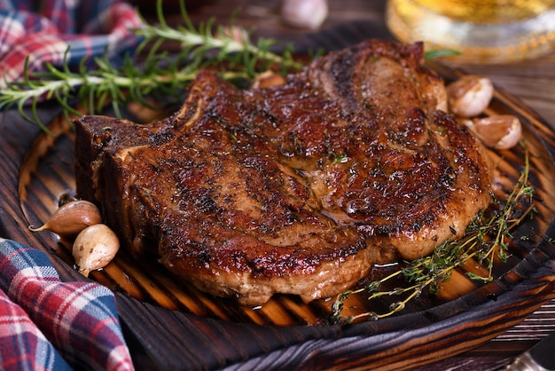 Geroosterde karbonade op de bone steak Het vlees wordt geserveerd op een houten bord met rozemarijn