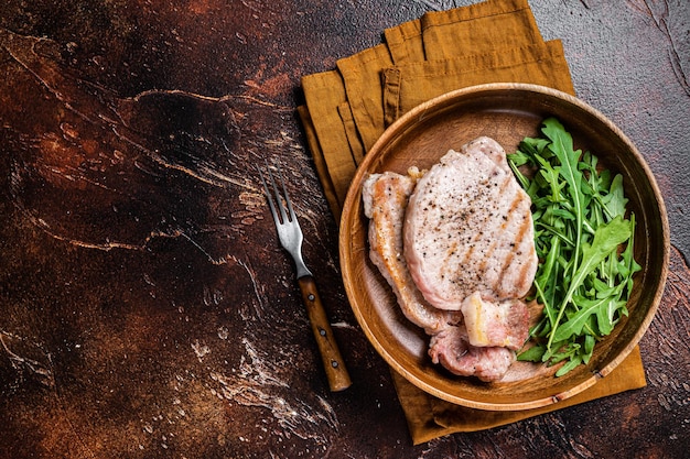 Foto geroosterde karbonadesteaks of schnitzels met rucolasalade donkere achtergrond bovenaanzicht ruimte kopiëren