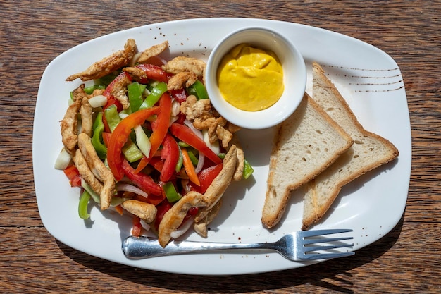 Geroosterde kipfilet met groenten en brood op een witte plaat close-up