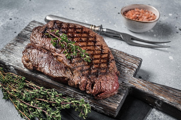 Geroosterde op grill top entrecote met rozemarijn en tijm Grijze achtergrond Bovenaanzicht