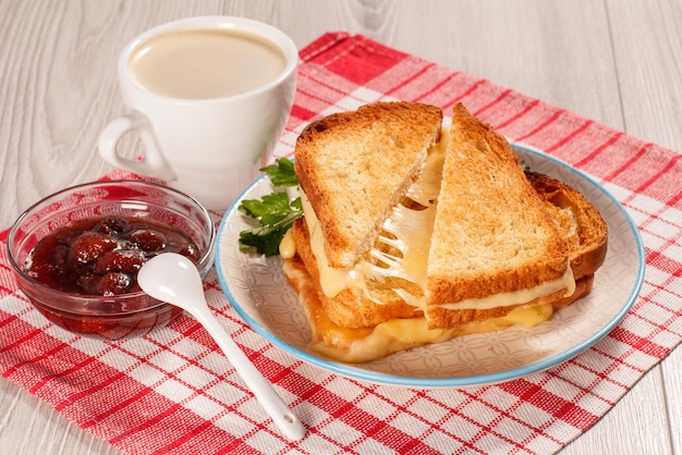 Geroosterde sneetjes brood met kaas en groene peterselie op witte plaat kopje koffie en lepel