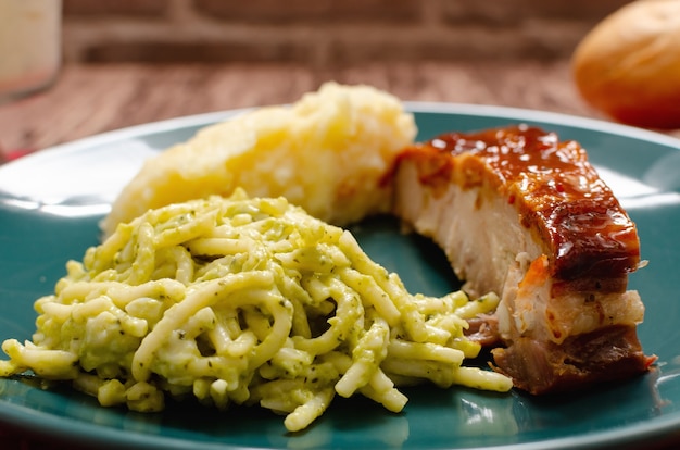 Geroosterde spareribs gemarineerd met barbecuesaus geserveerd met aardappelpuree, spaghetti en brood