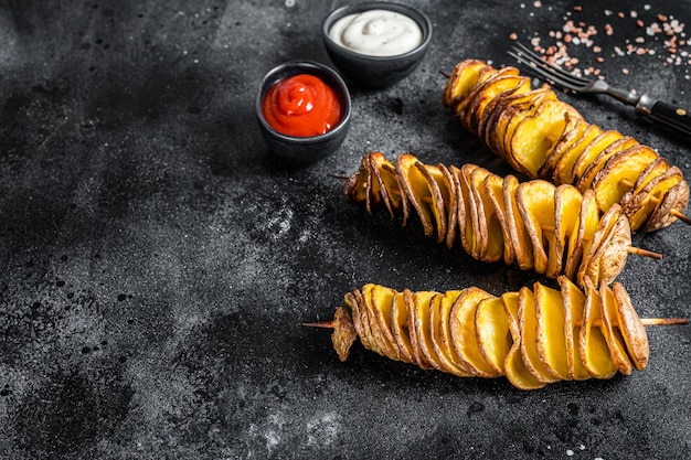 Geroosterde Tornado of gedraaide aardappelen met ketchupsaus. Zwarte achtergrond. Bovenaanzicht. Ruimte kopiëren.