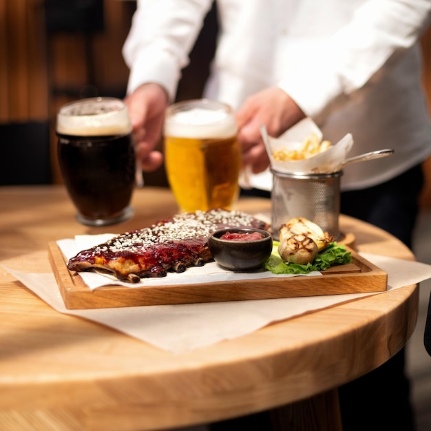 Geroosterde varkensribbetjes met knoflook en glas donker bier op bakpapier over rustieke houten achtergrond selectieve focus