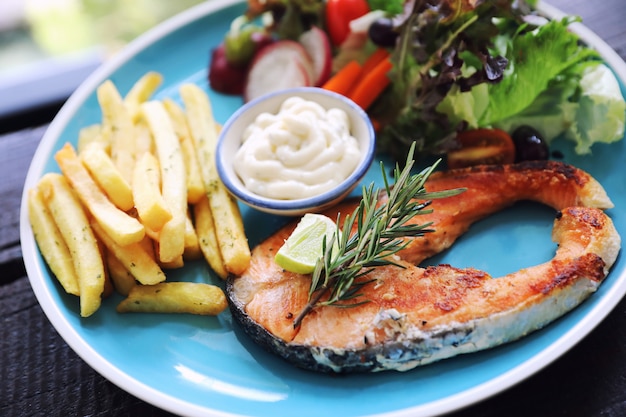 Geroosterde zalm steak, gebakken zalm met salade verse groenten pm houten tafel