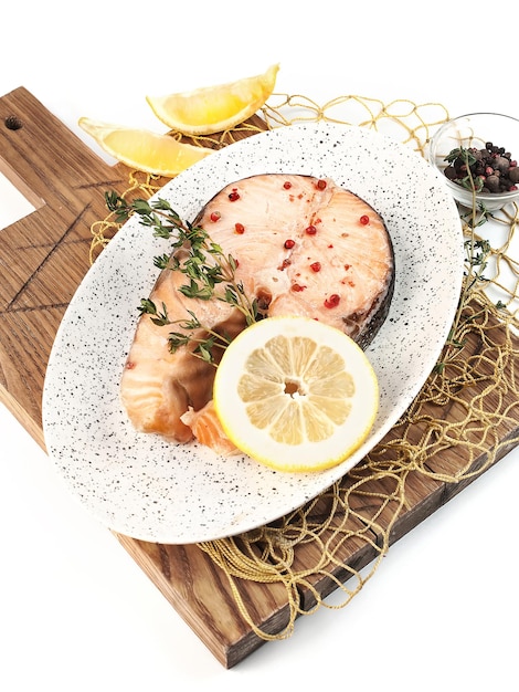 geroosterde zalm vis steak met citroen en kruiden op witte achtergrond