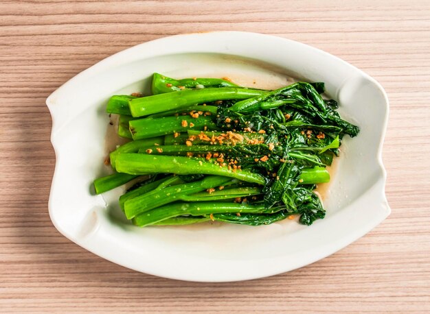 geruikte gebakken seizoensgebonden groenten Chinese broccoli of kai lan met gehakte knoflook geserveerd in een gerecht geïsoleerd op de tafel uitzicht op Hong Kong eten