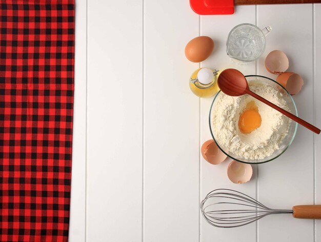 Geruit patroon voor het bakken van achtergrond met basisbakgereedschap en ingrediënten. Ei, ballongarde, bloem, olie en spatel aan de rechterkant, ruimte voor tekst kopiëren