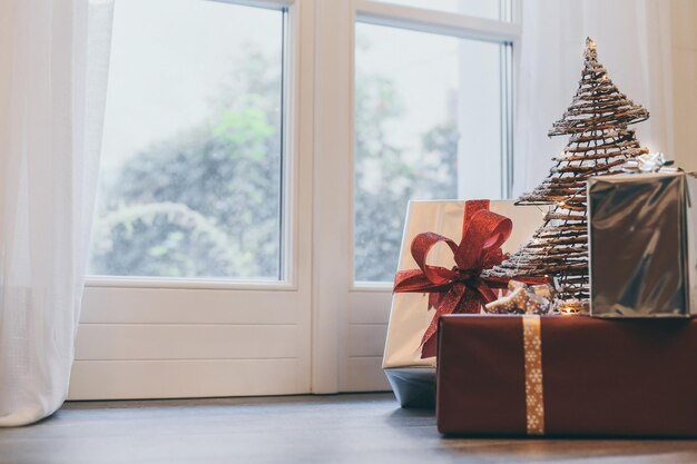 Geschenk dozen op de vloer bij de deur en kerstboom binnen huis doos met vakantie lint met strikken