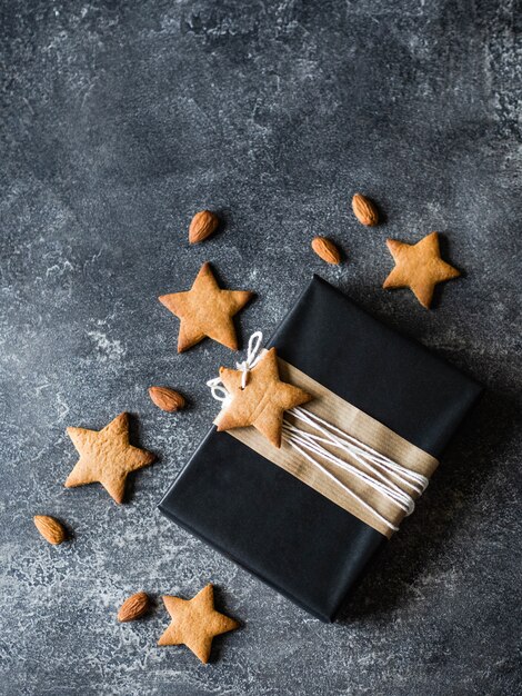 Geschenk in zwart inpakpapier en versierd met gemberkoekjes. Traditioneel idee voor het bakken en verpakken van kerstcadeaus