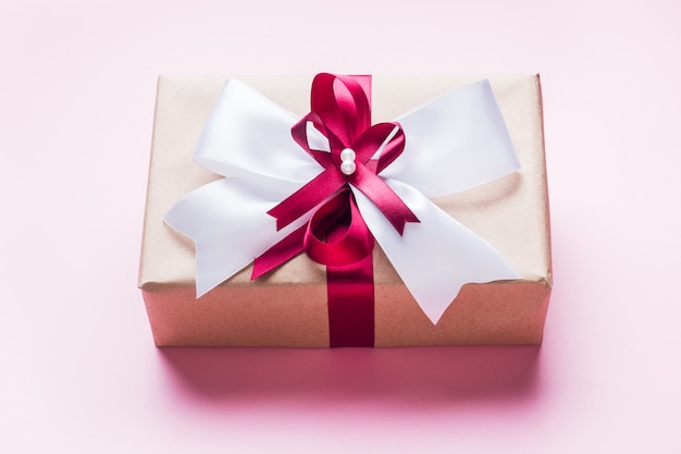 Geschenk of geschenkdoos met een grote strik op een roze tafelblad. Plat lag compositie voor Kerstmis, verjaardag, moederdag of bruiloft.
