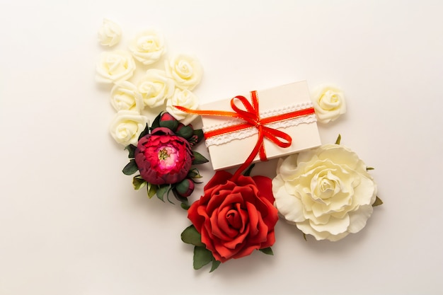 Geschenkdoos aanwezig decoraties flatlay. Geschenk, rood lint, rood roze bloemen bovenaanzicht