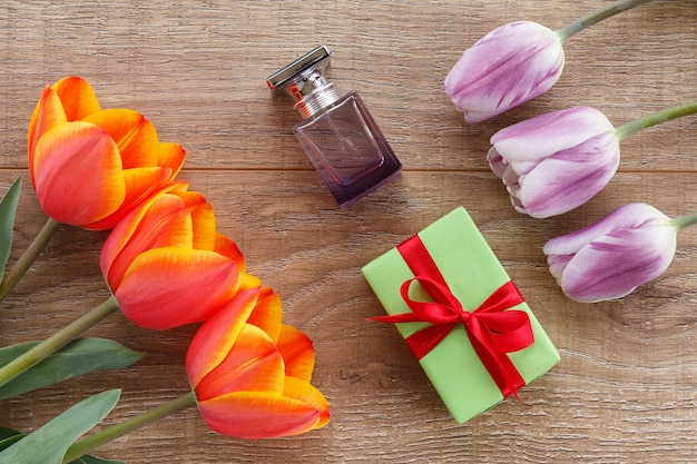 Geschenkdoos, een flesje parfum met rode en lila tulpen op de houten planken