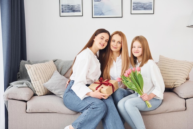 Geschenkdoos en bloemen Jonge moeder met haar twee dochters overdag thuis